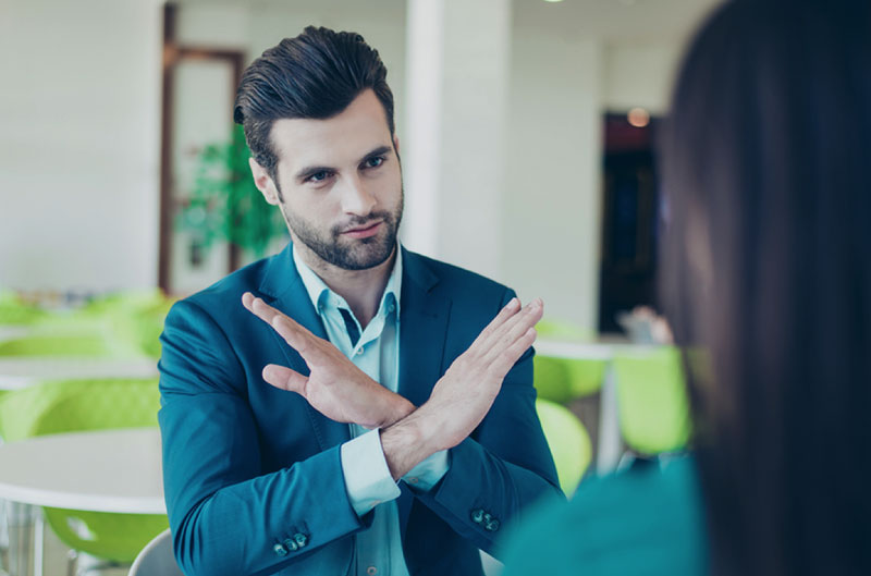 man crossing arms in refusal at a modern cafe