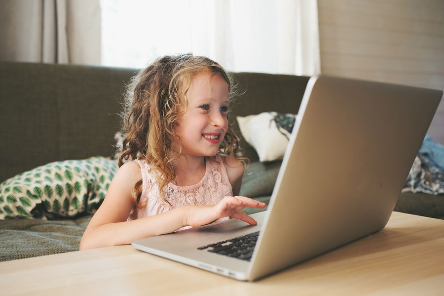 child smiling while using laptop in cozy living room