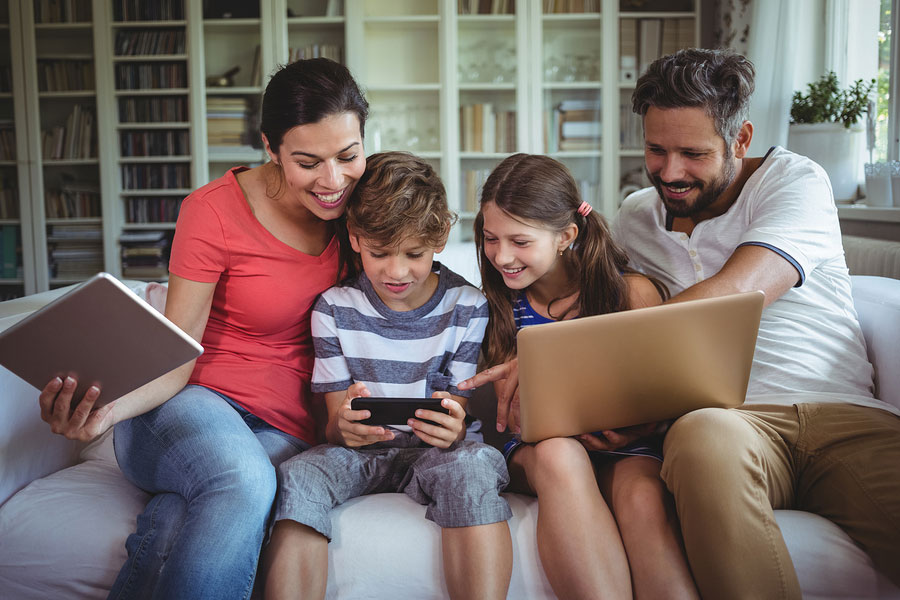 family using devices together on a cozy living room couch