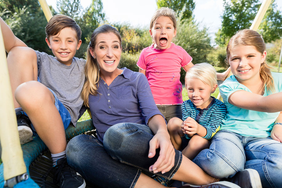 woman surrounded by smiling kids enjoying time at the park