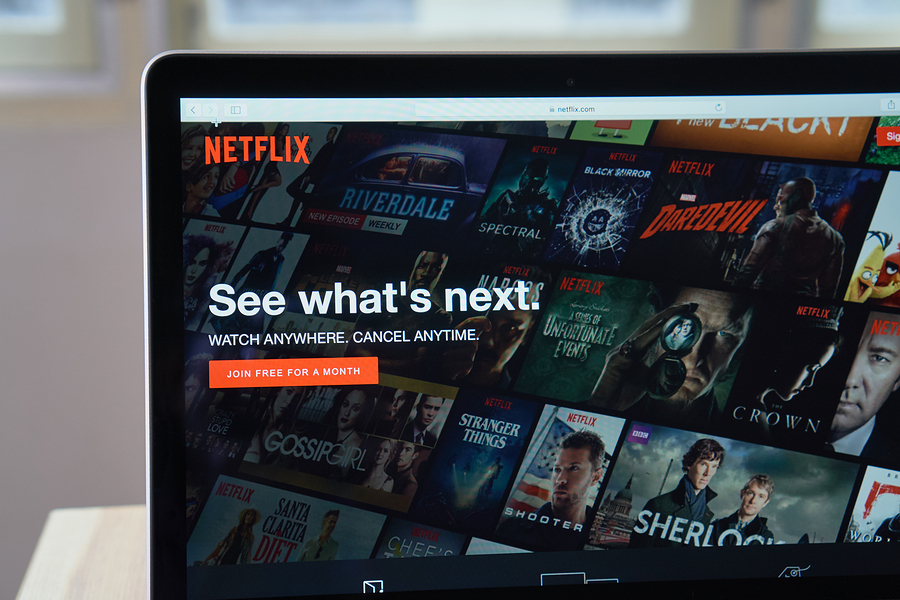 laptop screen displaying netflix homepage with various show titles.
