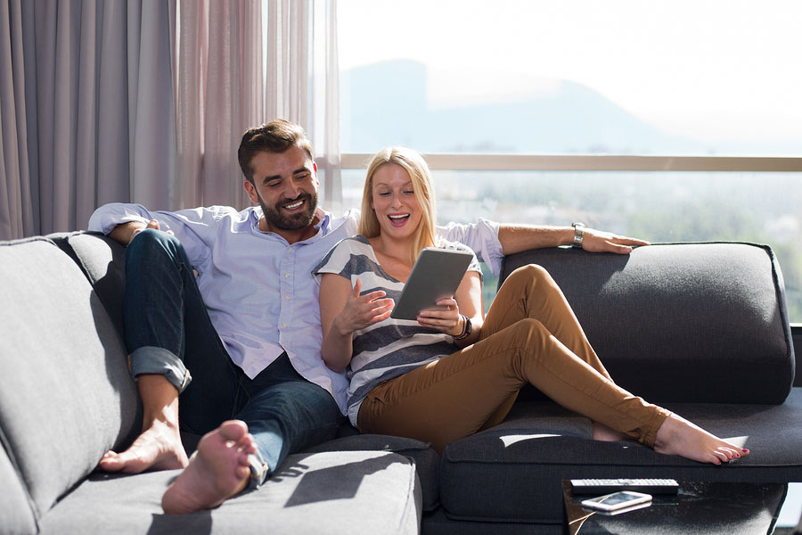couple lounging on sofa enjoying tablet indoors