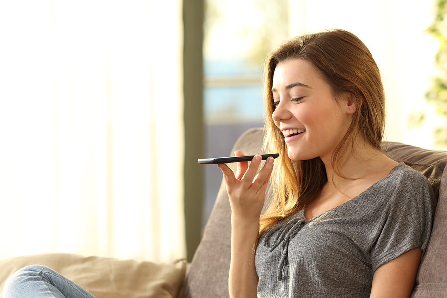 woman speaking into smartphone in a cozy living room.
