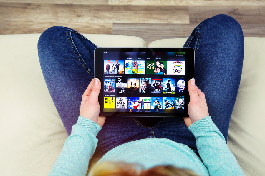 tablet browsing movie selection while relaxing on a sofa