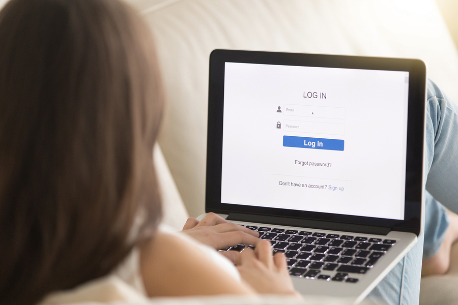 person using laptop for online login on a bed