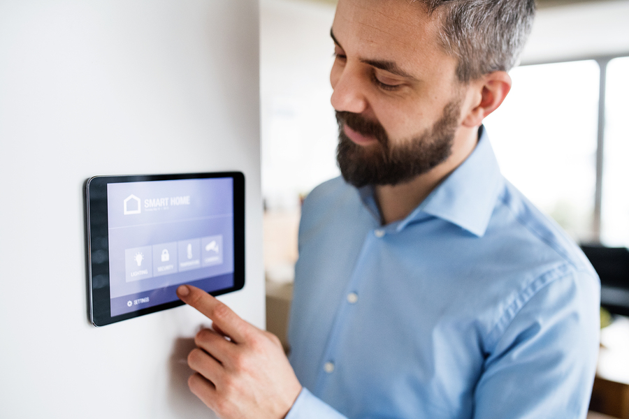 man operating smart home system on wall-mounted tablet device