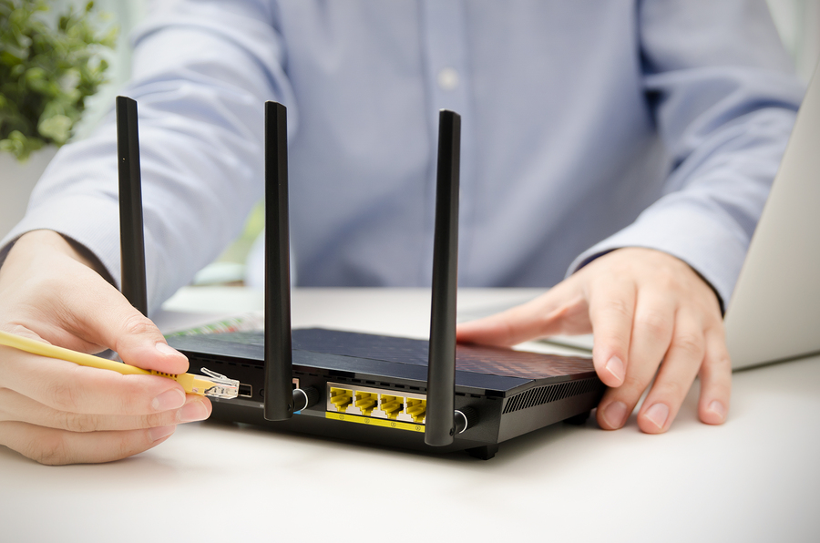 hands connecting ethernet cable to router on a desk