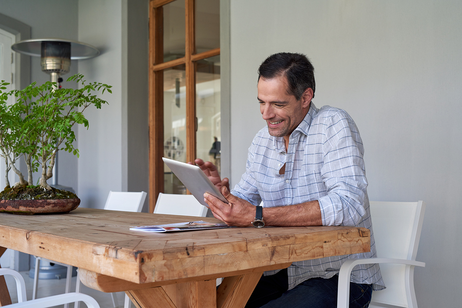 man using tablet at wooden table on a patio