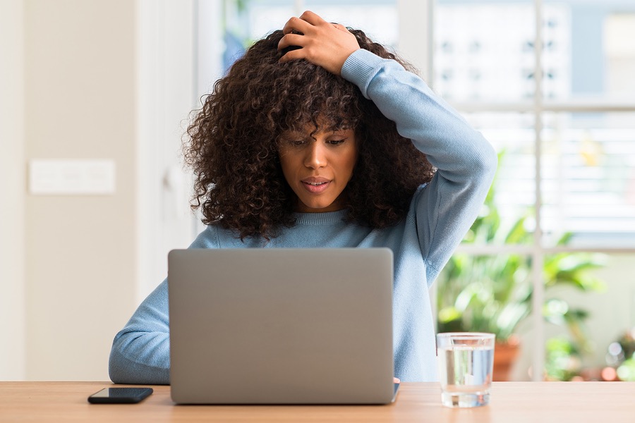 person using laptop, looking frustrated in home office setting