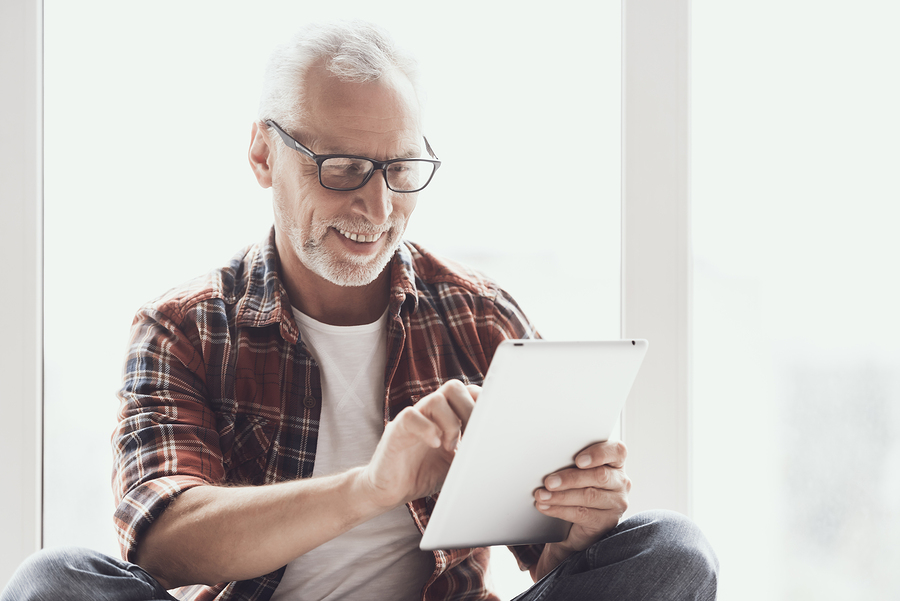 man using tablet near bright window
