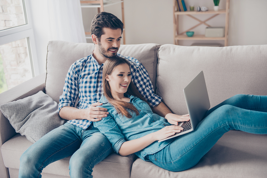 couple relaxing on couch using laptop in cozy living room