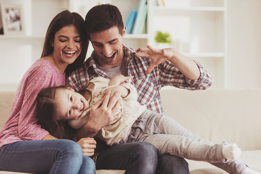 family laughing together on a cozy living room sofa