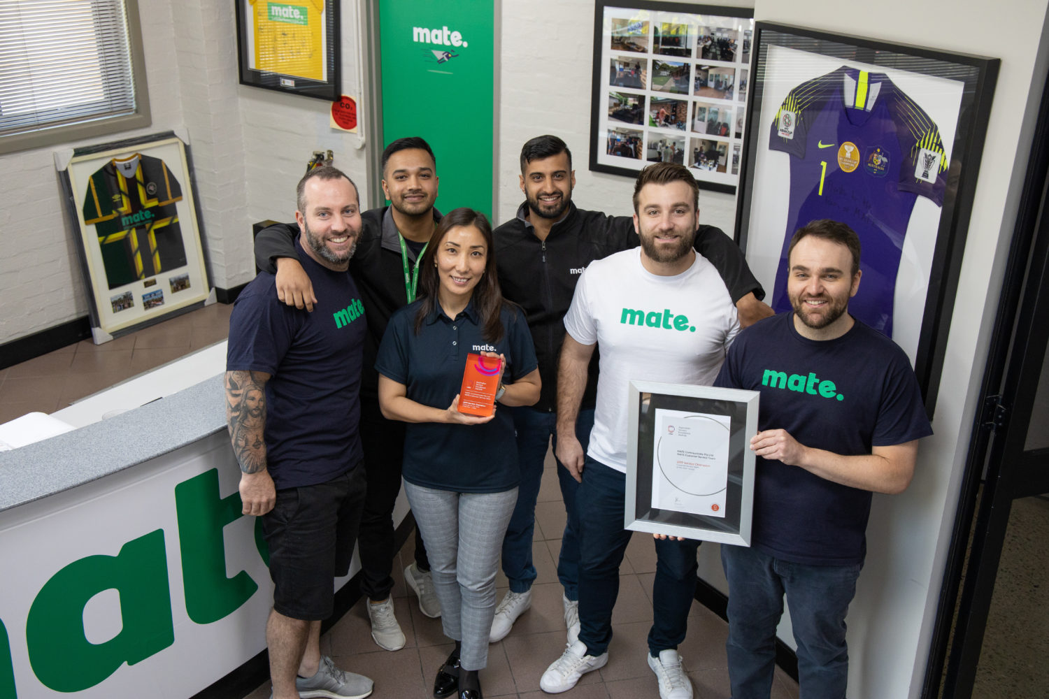 team holding awards by the mate brand in office setting
