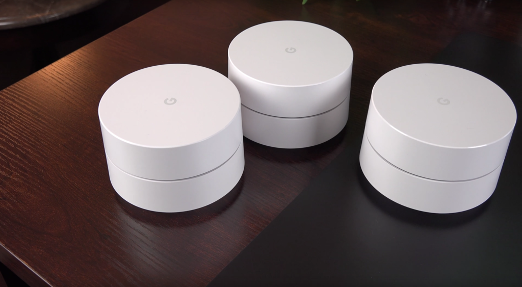 three white routers sitting on a wooden table by mate