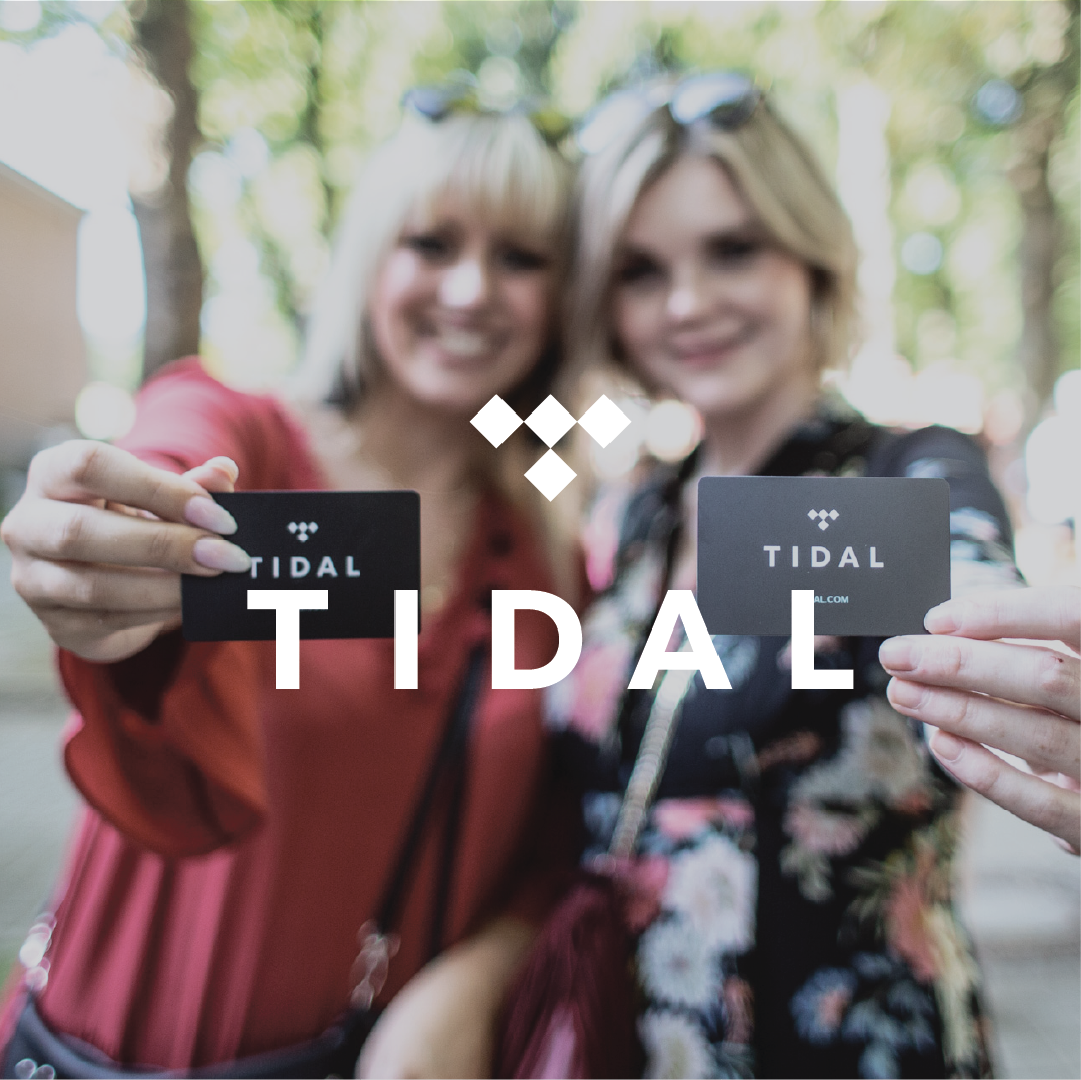 women holding tidal cards outdoors, showcasing brand promotion.