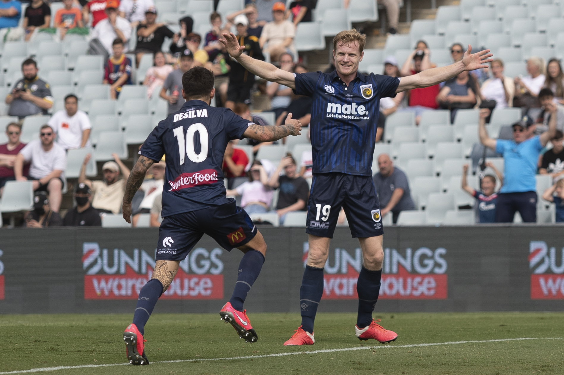 soccer players celebrating goal on field during match with cheering crowd