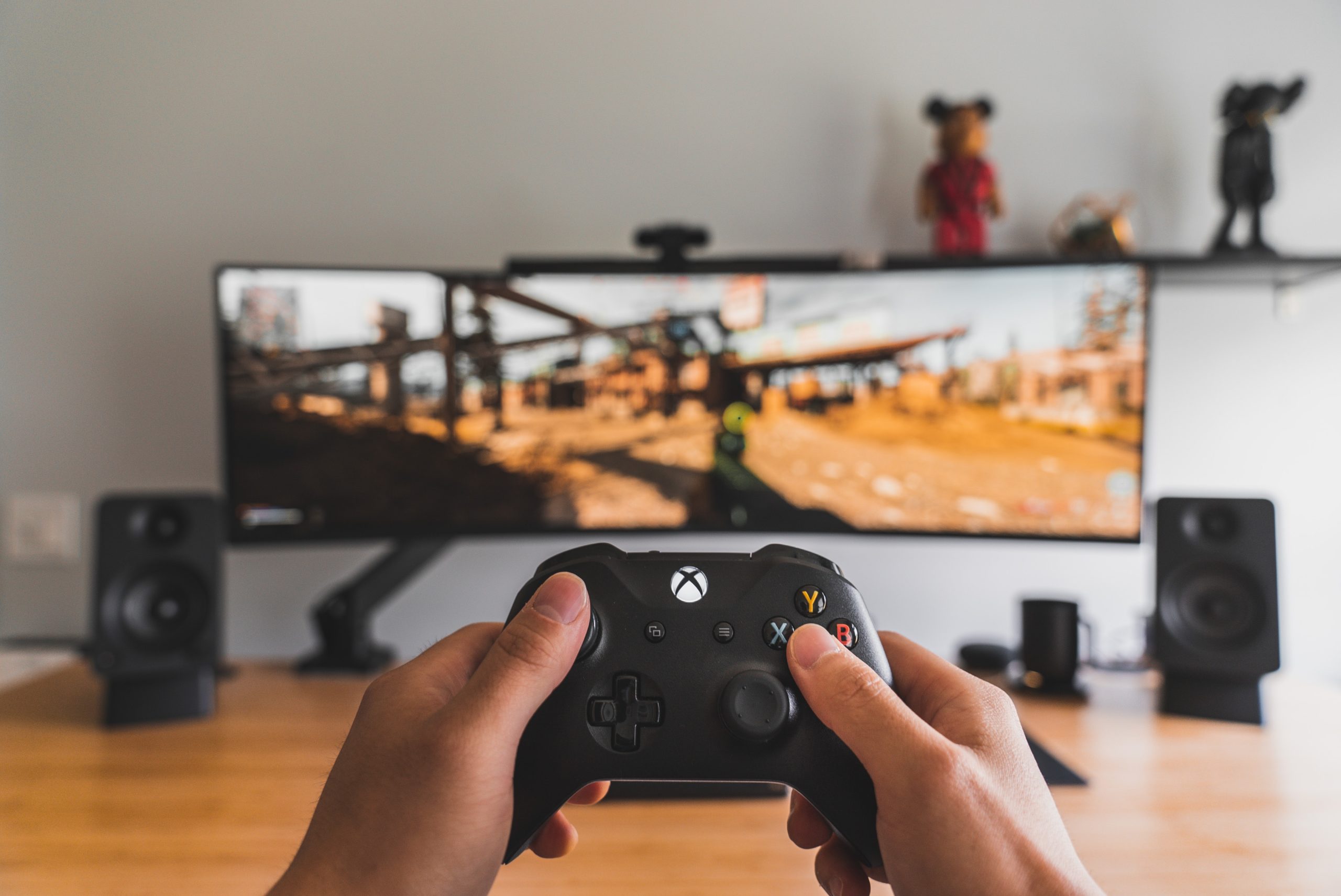 hands gaming with controller at desk setup with monitor