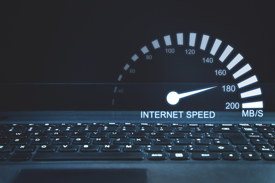 laptop keyboard beneath glowing internet speed gauge in dark setting
