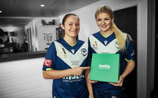 two athletes holding mate internet mobile box in a living room.