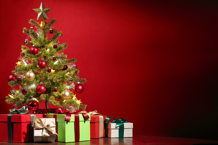 christmas tree decorated with ornaments beside wrapped gifts in festive setting.