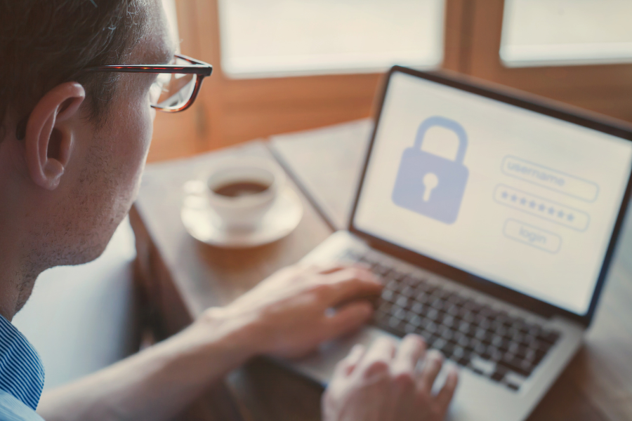 person typing login details on laptop at desk with coffee