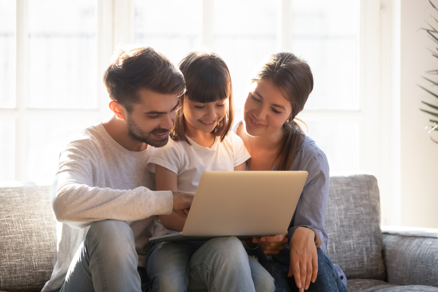 family using laptop together on cozy living room sofa