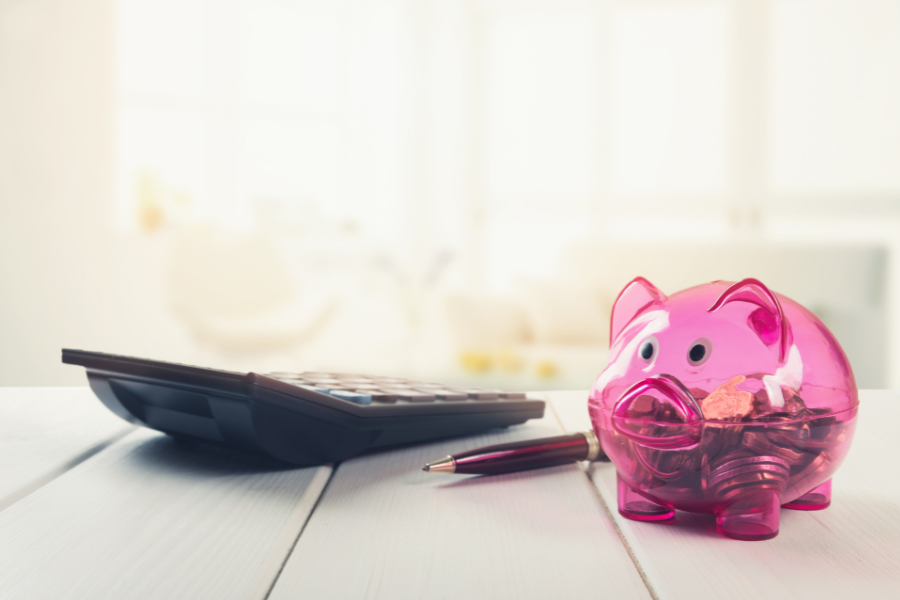 piggy bank saving coins near calculator on office desk