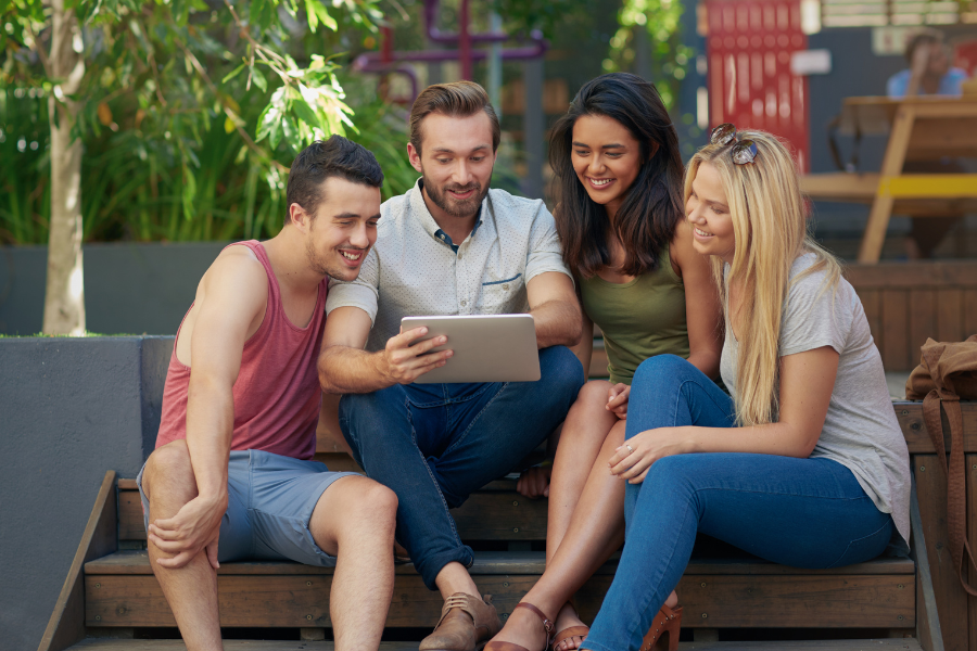 group of friends watching tablet on outdoor steps
