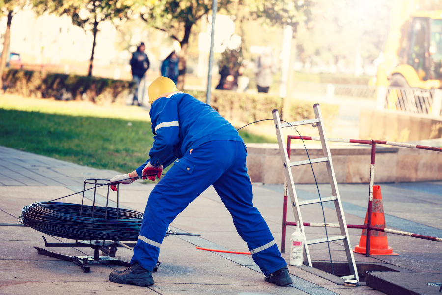 worker laying cable in a city street construction site