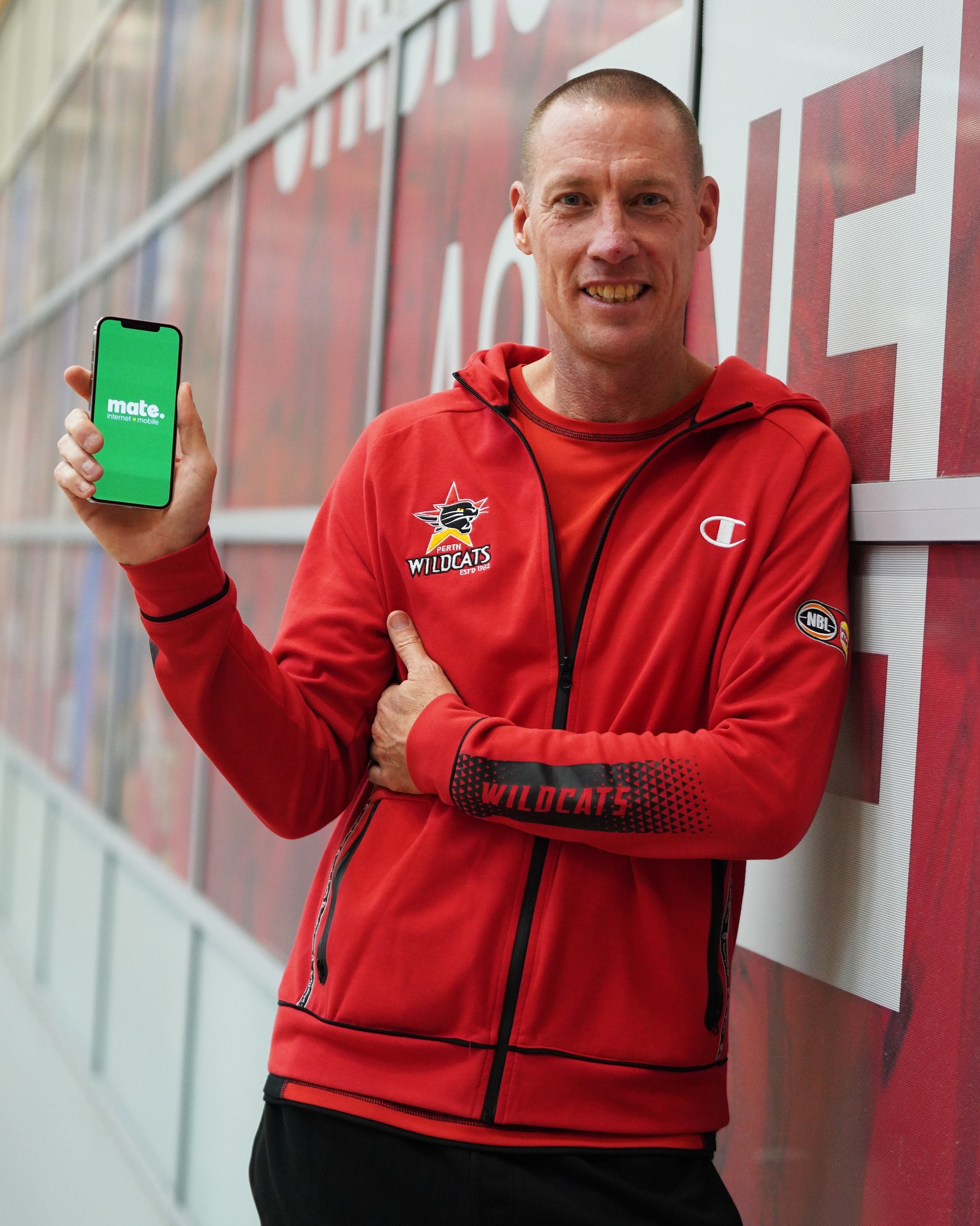 man holding smartphone with mate app by the perth wildcats.