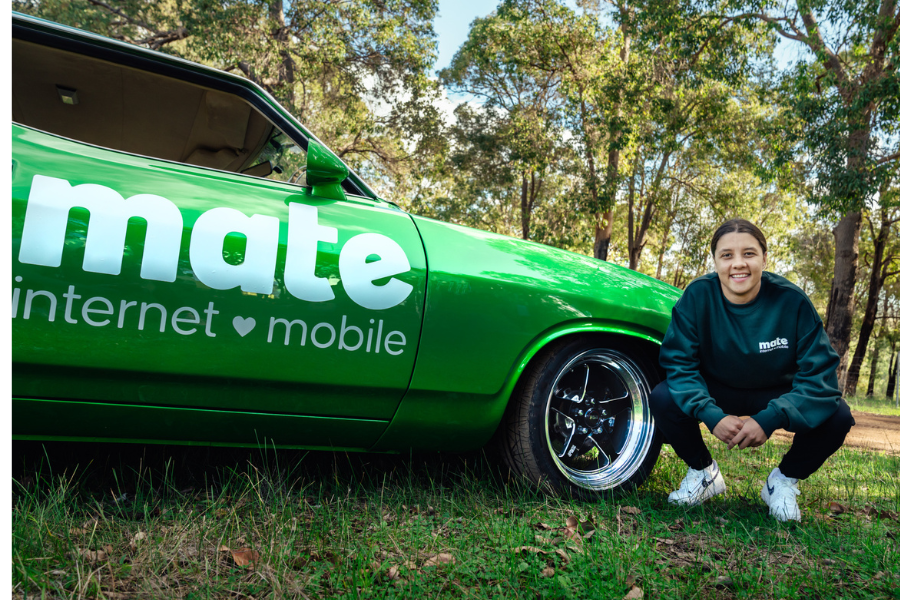 green car by mate with woman smiling in a park.
