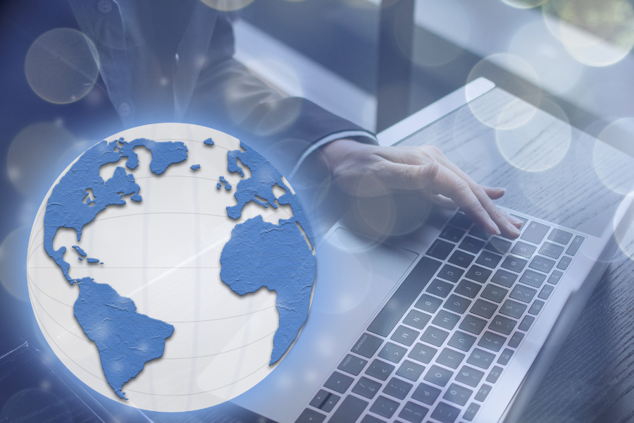 person typing on laptop with globe overlay in modern office