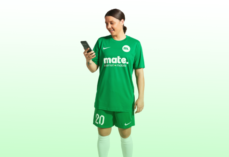 soccer player reading phone, wearing green mate uniform.