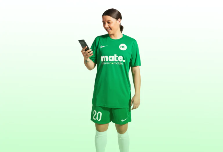 soccer player reading phone, wearing green mate uniform.